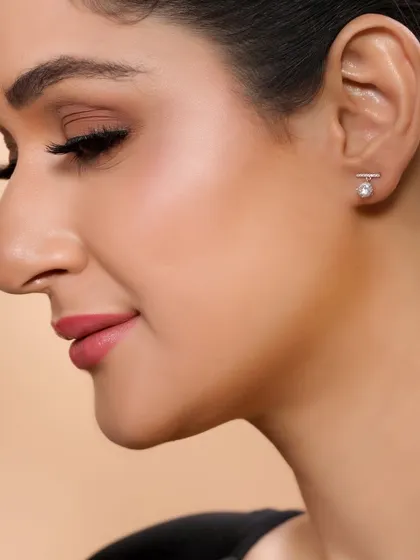 A side-profile shot highlighting a pair of modern, minimalist earrings. This angle provides a clear view of the design and how it looks when worn.