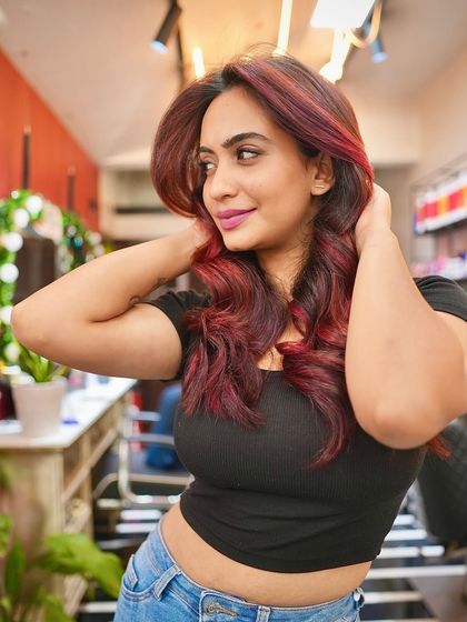 Urvashi enjoying her new red hair in the salon. The color complements her style perfectly, and she’s ready to rock this look with confidence.