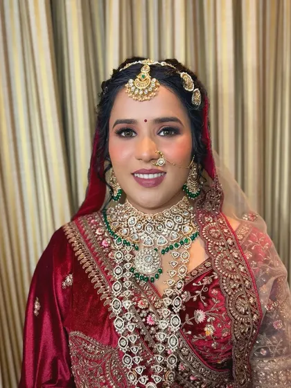 A portrait of bridal beauty. The bride's makeup is glamorous, with smoky eyes and a matte lip, perfectly complementing her heavy jewelry and velvet attire.
