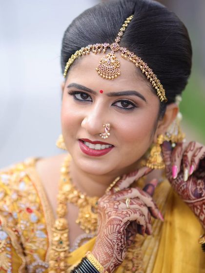 A bright, happy close-up of Rashmi. The makeup is fresh and radiant, with a bold red lip that perfectly suits a bridal look.