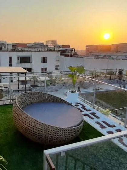 The terrace is the best place to witness a beautiful sunset. This design features a large wicker daybed overlooking the city, set on a lush artificial lawn.