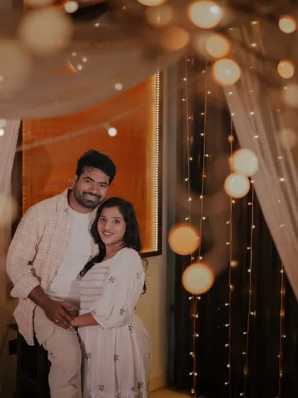 The indoor bed set with fairy lights and curtains provides a soft, dreamy backdrop for this couple's tender moment.