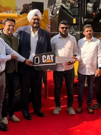 The culmination of a successful product launch. Here, the team celebrates the handover of a new Caterpillar machine, a key moment captured in a professionally staged event environment.