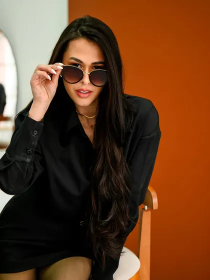 A model in a chic black outfit peers over her sunglasses, exuding confidence and mystery. This shot captures the sleek, urban vibe of Mumbai's fashion scene, perfect for lifestyle and brand campaigns.