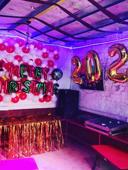 I help cafes and restaurants get ready for the holidays with festive decor, such as this 'Merry Christmas' balloon wall combined with purple mood lighting for a New Year's 2023 party.