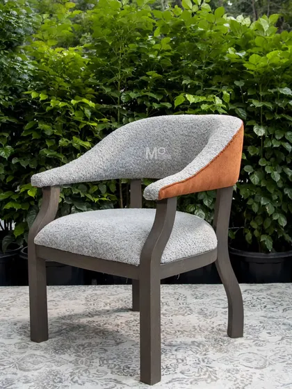 The Versa Armchair is a seamless blend of comfort and modern design. Upholstered in soft bouclé with a rich burnt orange accent, its solid ash wood frame features a unique zig-zag inspired leg design, celebrating materiality, form, and function.