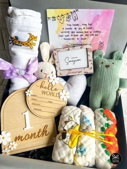 This pastel-themed 'bundle of love' hamper is perfect for a newborn. It includes wooden milestone cards, a sonogram frame, soft toys, and a personalized announcement card.