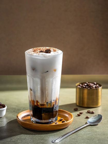 A layered iced coffee with a creamy foam top, shot in a minimalist and modern style.
