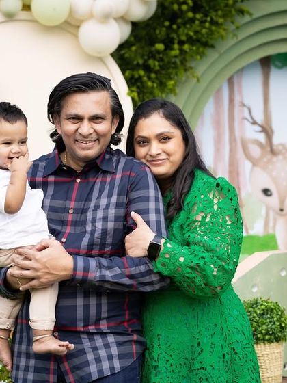 A happy family photo at Advaith's woodland party, with the birthday boy and his parents posing in front of the themed backdrop.