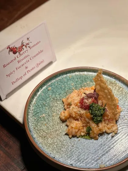 Roasted Cherry Tomato Risotto, a delicious Jain option. We ensure our special dietary menus are just as flavourful and beautifully presented, using ingredients like spicy focaccia crumble and a dollop of pesto.