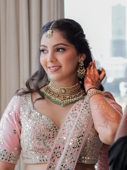 Adjusting her jewelry, this bride looks effortlessly elegant. The makeup is designed to be beautiful from every angle.