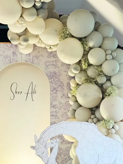 The main backdrop for the Sher Ali's 'Wild One' birthday, showing the custom name sign, giraffe cutout, and a sophisticated white balloon arch.