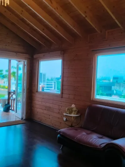 Another angle of the New Friends Colony wooden cottage, showing the seamless transition from the indoor space to the outdoor terrace garden through large sliding doors.