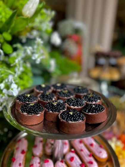 The caviar tarts presented on a silver stand, below a tier of raspberry eclairs, showing the blend of savory and sweet.