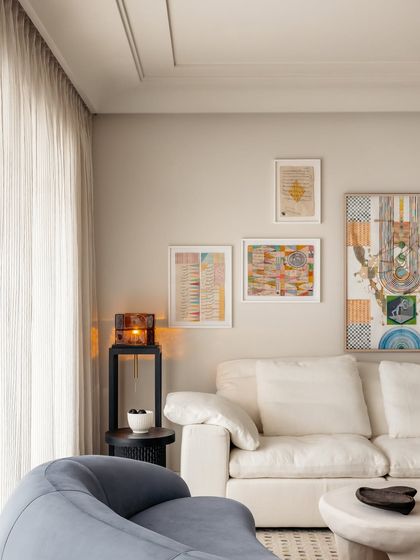 Another view of the living and dining space, highlighting the colorful artwork and the light, airy feel created by the large windows and sheer curtains.