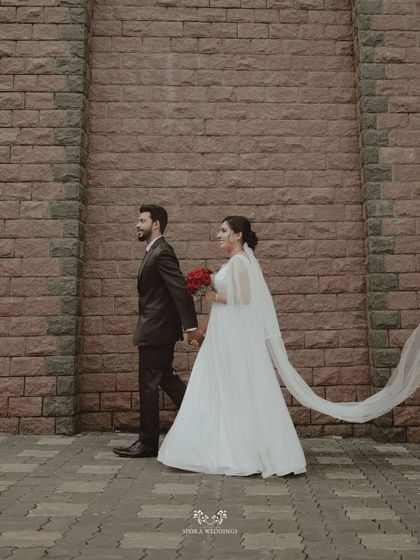 The couple walking together, the bride's long veil trailing behind them in a graceful, flowing motion.
