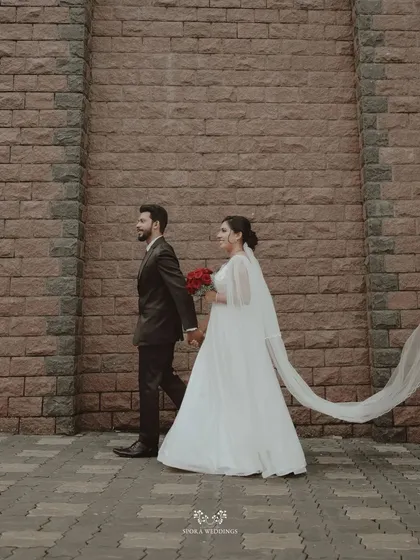 The couple walking together, the bride's long veil trailing behind them in a graceful, flowing motion.
