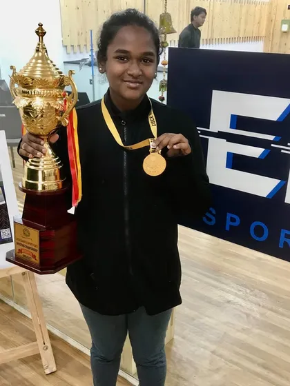 A proud moment for our champion, Leno Caroline, holding her gold medal and the winner's trophy. We celebrate these victories to inspire all our athletes.