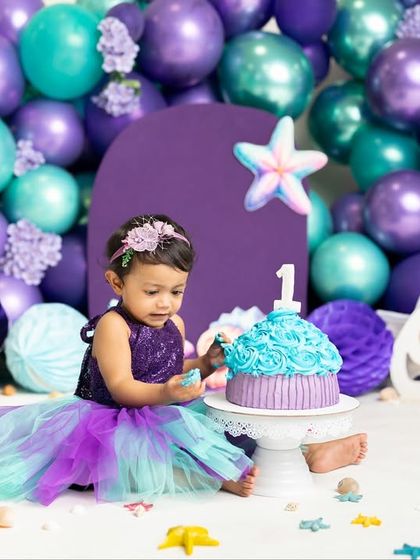 Getting a little taste of that first birthday cake! This little mermaid is curiously exploring her beautiful blue and purple cake during her themed smash session.