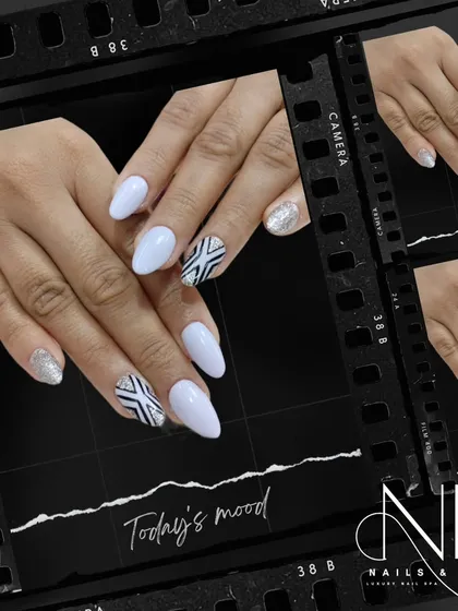 A modern black and white design. This look pairs clean white nails with a geometric, aztec-inspired pattern and a silver glitter accent nail.