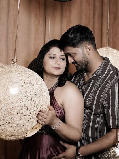 An intimate embrace in a room with warm lighting and unique spherical lamps, creating a cozy and modern feel.