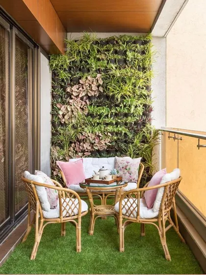 A lush vertical garden serves as a living art piece in this balcony. Paired with artificial grass flooring and comfortable cane furniture, it creates a fresh, botanical-themed seating area that feels like a private garden.