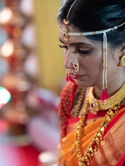 A close-up of the bride during her ceremony. You can see the detail in the eye makeup and the traditional 'mundavalya' (forehead jewelry) that is essential to the Maharashtrian bridal look.
