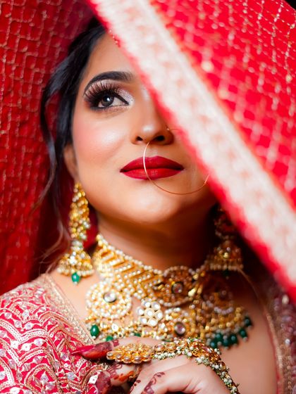 A stunning close-up through the veil, focusing on the bride's eyes and the bold red lip.