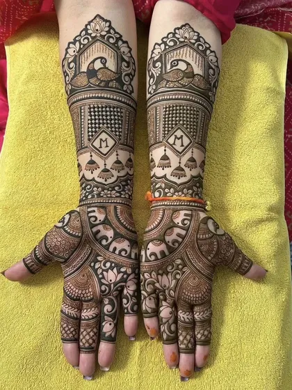 A classic bridal design featuring majestic peacocks at the wrist and personalized initial 'M' on the palm. The pattern combines animal motifs with traditional jhumka (earring) designs.