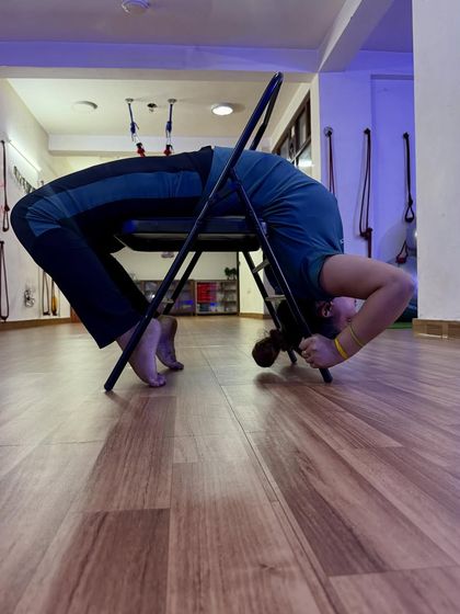 Strong women wear their pain like stilettos. A deep backbend over a chair, a pose that requires immense strength and flexibility.