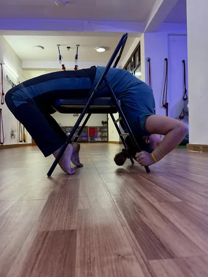 Strong women wear their pain like stilettos. A deep backbend over a chair, a pose that requires immense strength and flexibility.