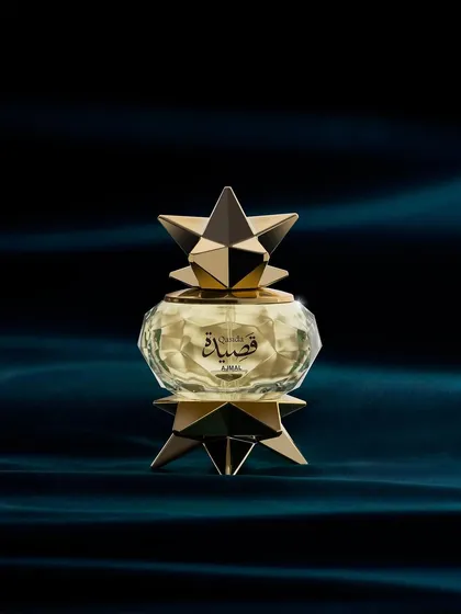 This Ajmal perfume bottle looks like a star from another galaxy. I placed it against a deep, velvety blue fabric and used soft, focused light to highlight its intricate, geometric gold structure and the faceted glass.