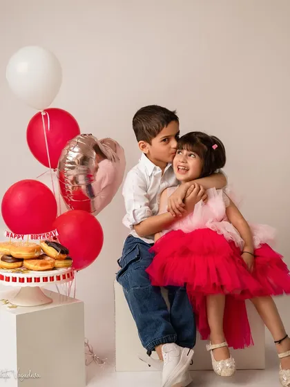 The sweetest sibling hug. Her big brother gives her a kiss on the cheek during her 4th birthday shoot, a heartwarming moment of love and connection.