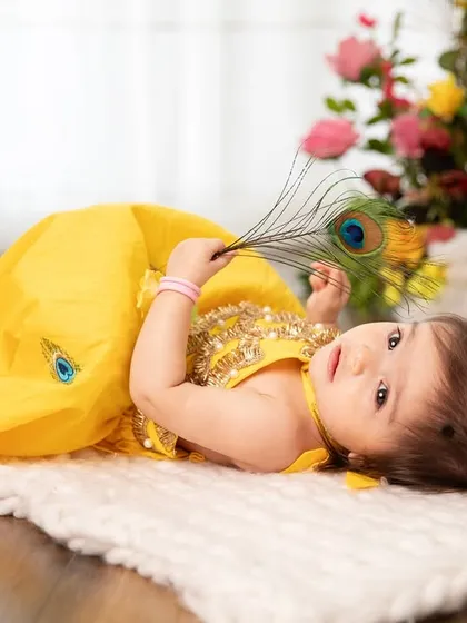 Lying down with a peacock feather, this tiny Radha looks so peaceful. The yellow dress and floral elements create a bright and cheerful atmosphere.