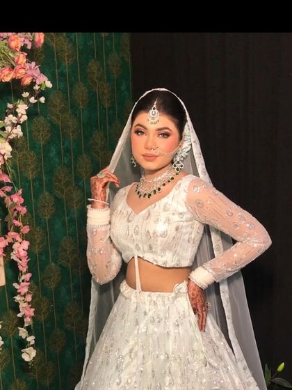 A three-quarter view of the white lehenga, highlighting the sheer embroidered sleeves.