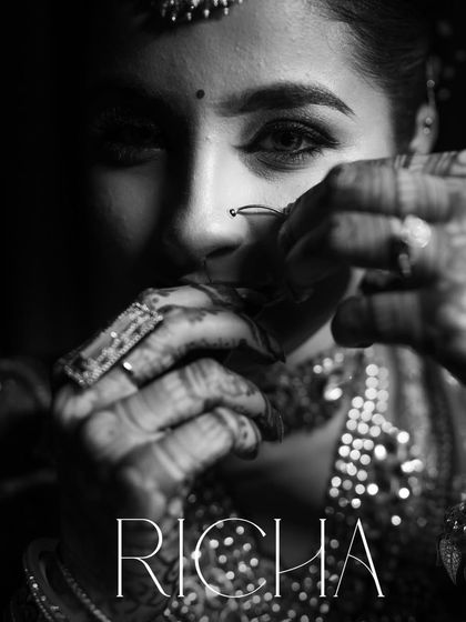 A close-up, artistic black and white shot of the bride, Richa, adjusting her nose ring. This highlights the beautiful details of her reception look.