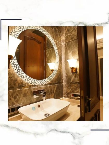 An ornate, circular mirror with a patterned frame serves as the focal point in this powder room. Paired with classic wall sconces, it adds a touch of glamour and sophistication.