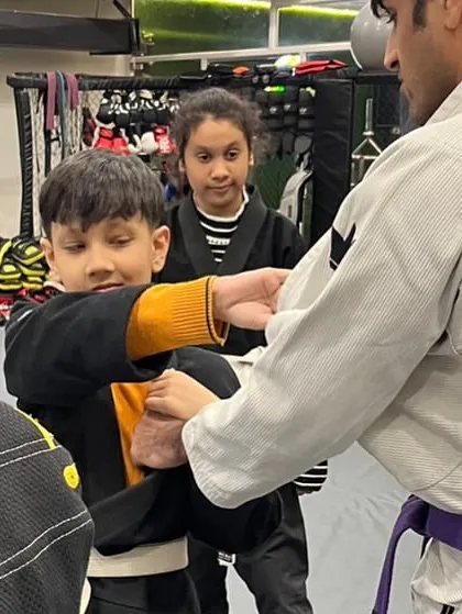 A young student learns a wrist control technique from the coach. This is a practical self-defense move that teaches children how to handle a situation where someone grabs them.
