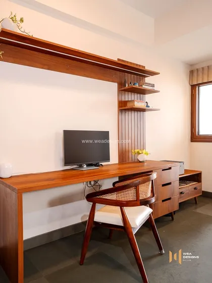 A larger study and media unit in the same earthy-themed home, with a long wooden desk, drawers, and open shelving for a complete workstation.