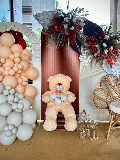 A complete view of one of the photo corners from the boho-themed event. The setup includes a large teddy bear, a stylish rattan chair, and balloon arrangements against custom-made backdrops.