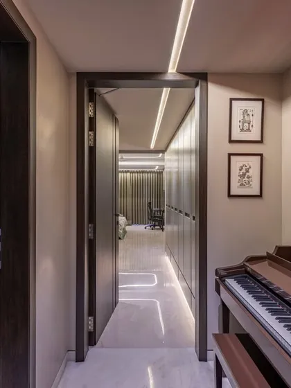 A bold red artwork and a classic piano create a striking cultural corner in this home. This passage connects different zones while serving as an artistic statement in itself.
