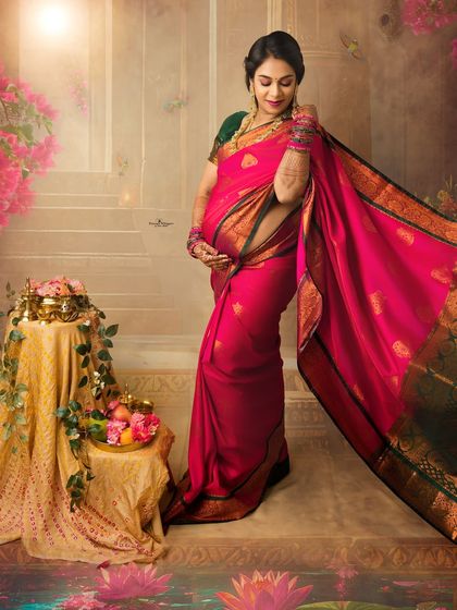 A full-length portrait showcasing the elegance of a traditional pink silk saree. The flowing fabric and graceful pose create a stunning visual against the painterly backdrop.