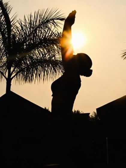 A silhouette of a guest practicing yoga against the golden light of the setting sun. This powerful image represents finding balance and strength as day transitions into night, a perfect moment for reflection.