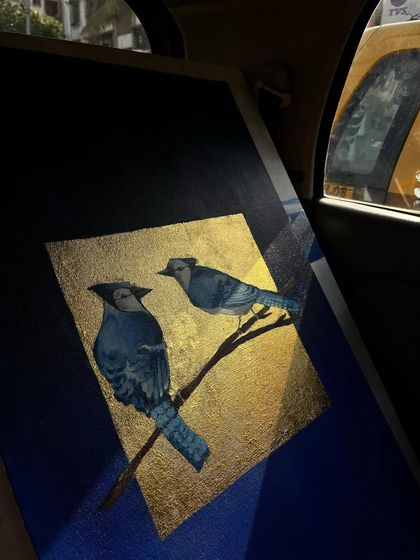My blue jay painting seen in the back of a taxi at night. The way the streetlights catch the gold leaf shows how the artwork transforms in different lighting conditions.