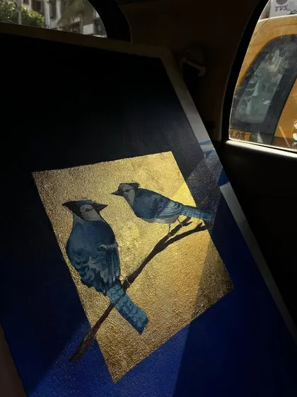 My blue jay painting seen in the back of a taxi at night. The way the streetlights catch the gold leaf shows how the artwork transforms in different lighting conditions.