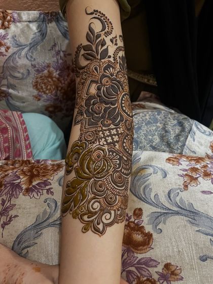 The upper arm portion of a bridal mehndi piece. The design continues seamlessly from the hand, creating a complete and cohesive look.