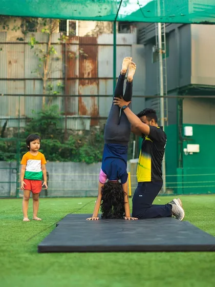 A snapshot from our first gymnastics session, with a young student learning the basics of handstands with a coach's guidance.