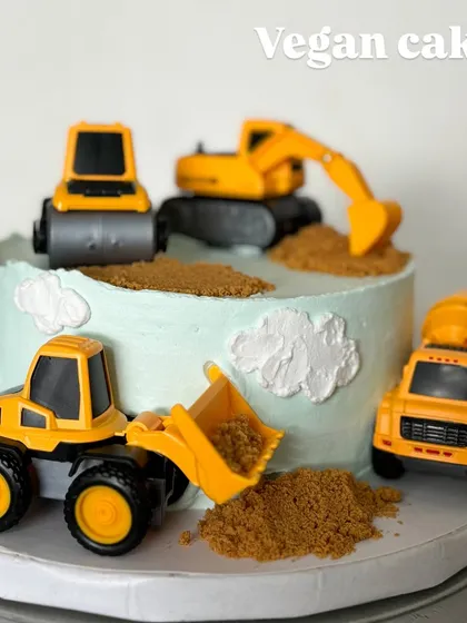 A construction-themed cake for a little builder. This is a completely vegan cake, decorated with fun toy trucks and edible "dirt" for a memorable birthday.