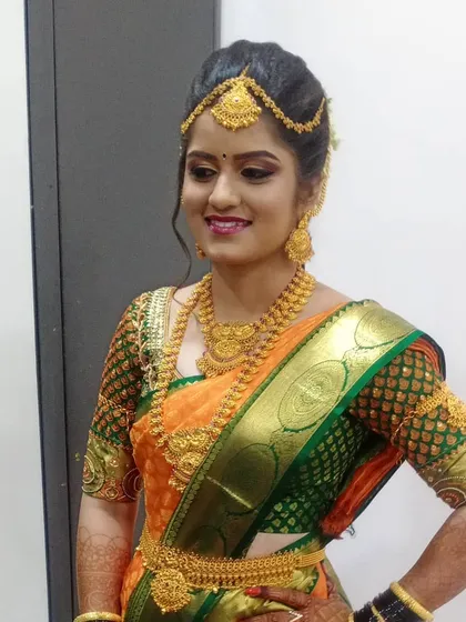 A complete bridal look featuring a vibrant orange and green Kanjeevaram saree. I ensured the makeup, with its warm tones and defined eyes, perfectly matched the richness of her outfit and traditional gold jewelry.