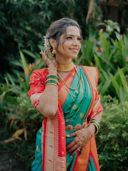 A smiling bride in her beautiful saree. The makeup is fresh and dewy, with a touch of flowers in her hair to complete the look.